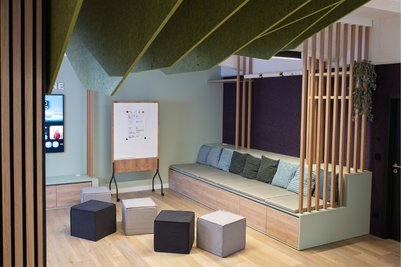 LMZ Ideenbühne Sitzbank Atelier Türke Ideenbereich mit Sitznische, Whiteboard und flexiblen Sitzwürfeln unter markanter Deckenstruktur. Kommunikatives Raumkonzept und Gestaltung von Atelier Türke entwickelt.