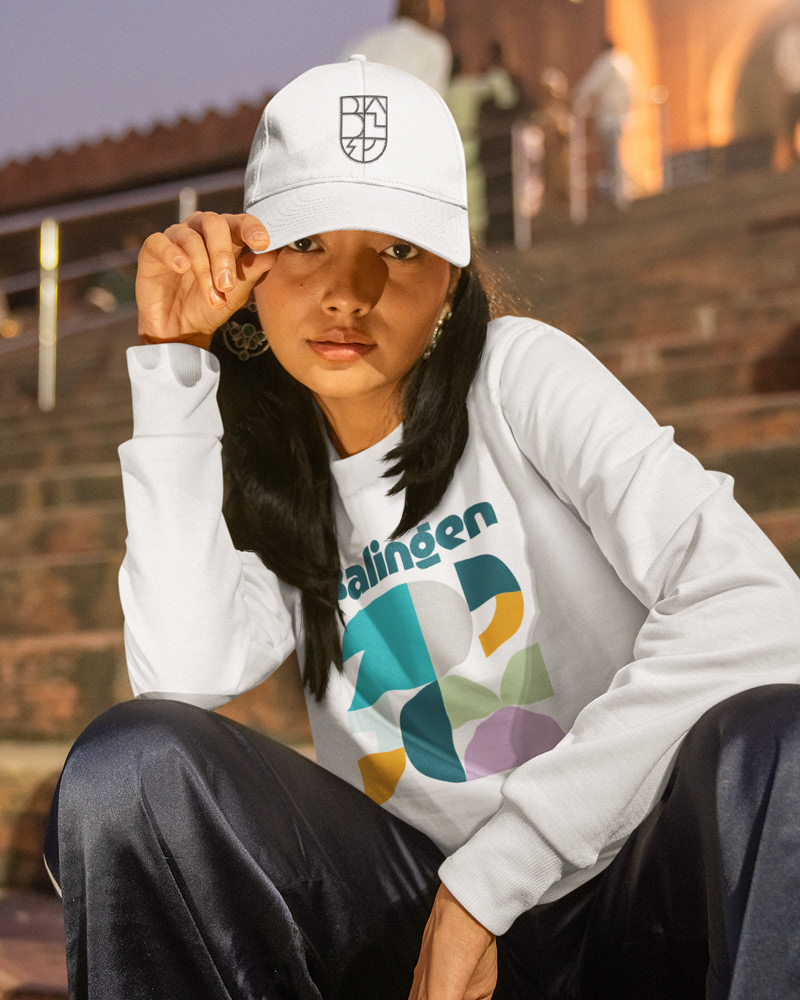 Balingen neues Design Merch Atelier Türke Frau mit Balingen Cap und Shirt im Corporate Design, das Atelier Türke etnwickelt hat. Für eine moderne und identitätsstiftende Markenanwendung.
